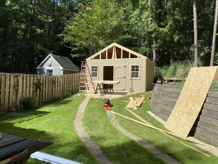 Our crew partway through building a wood shed in a customer's backyard, with the walls up and the roof framing in place