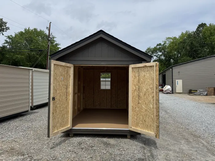 Inside a wood shed with the double doors open, showing the framed walls, floor and back window